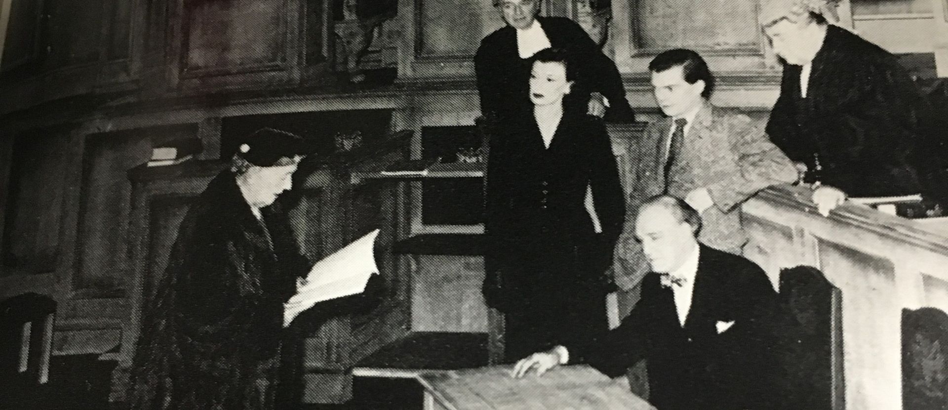 A play with people in a courtroom listening to talks.