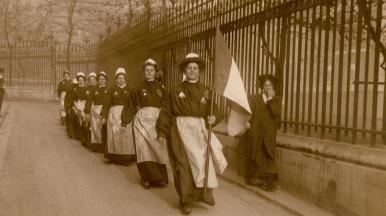 A group of suffragettes wearing prison uniform and marching down past the Royal Courts of Justice on what is now LSE campus.
