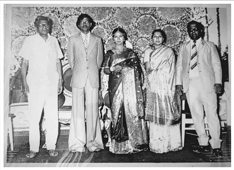 A wedding photograph including 5 people dressed up and posed for the camera