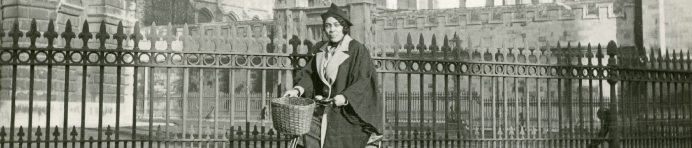 A woman wearing academic dress on a bicycle in Oxford