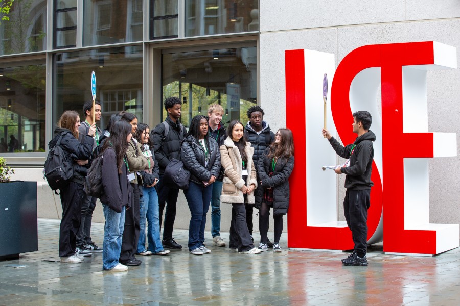 A group of people stood outside the Marshall Building by a big LSE sign.