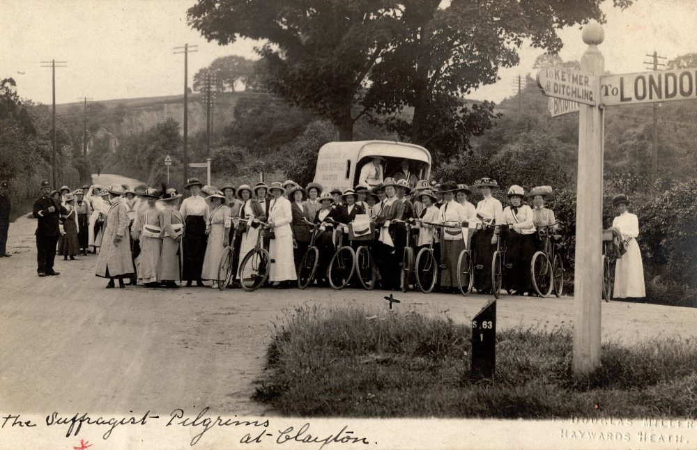 A large group of suffragist cyclists stood on a countryside road