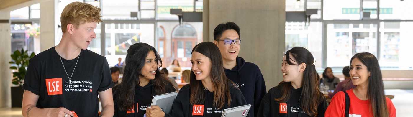 six department of management student ambassadors talking and walking through the Marshall Building ground floor
