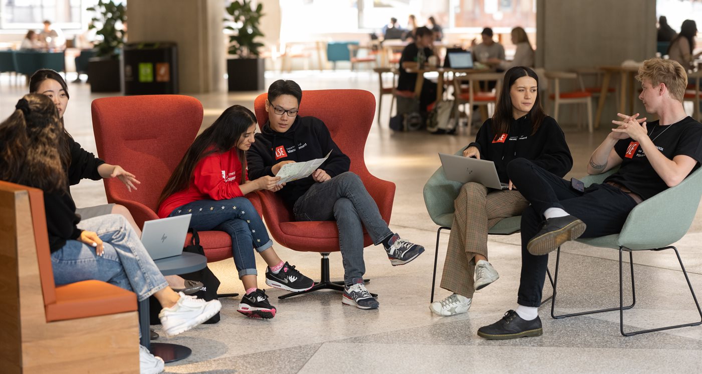 masters students sitting and talking in the great hall, Marshall Building on LSE campus