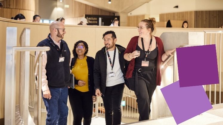 Group of students chatting and smiling as they walk up the stairs in the Marshall Building.