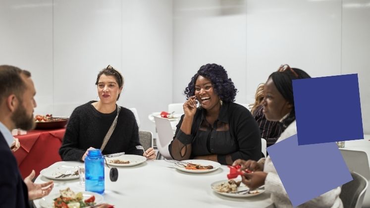 Group of students sitting eating lunch smiling and chatting.