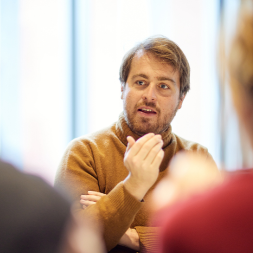 Male student talking to a panel of people off camera