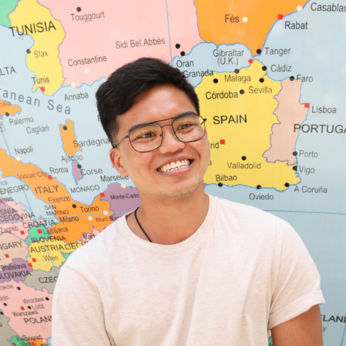 Male student smiling in front of a globe