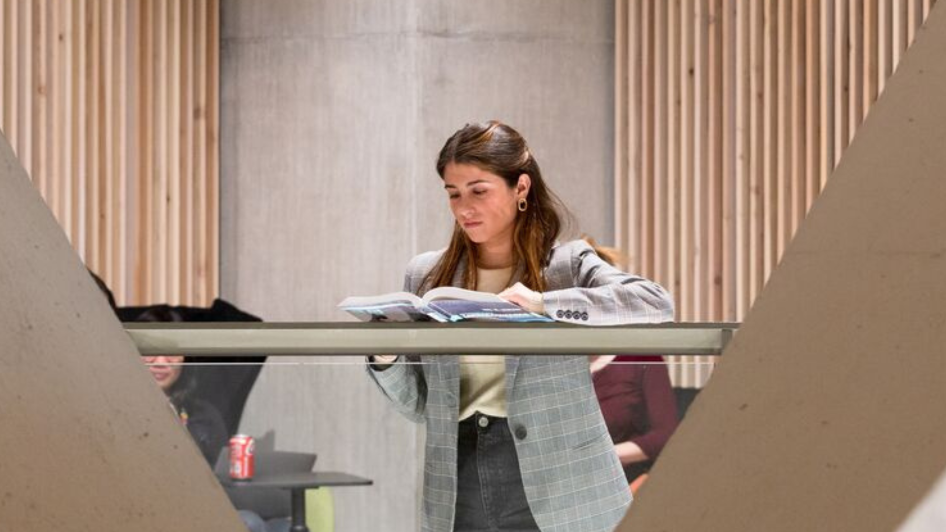 Female student reading a book inside the Marshall Building