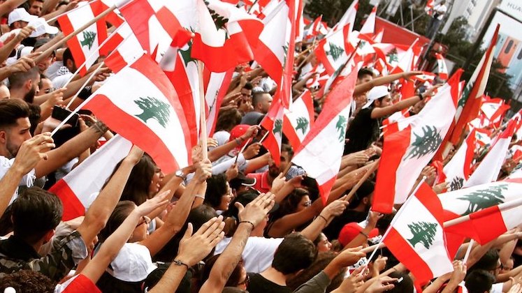 Protestors raising Lebanon's flag, which is red and white striped with a green cedar tree in the middle white stripe.
