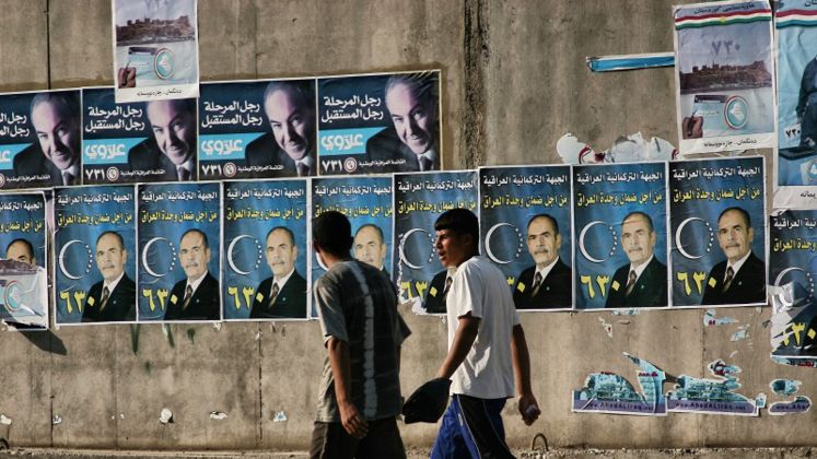 Two men walking next to a wall plastered with political campaign posters