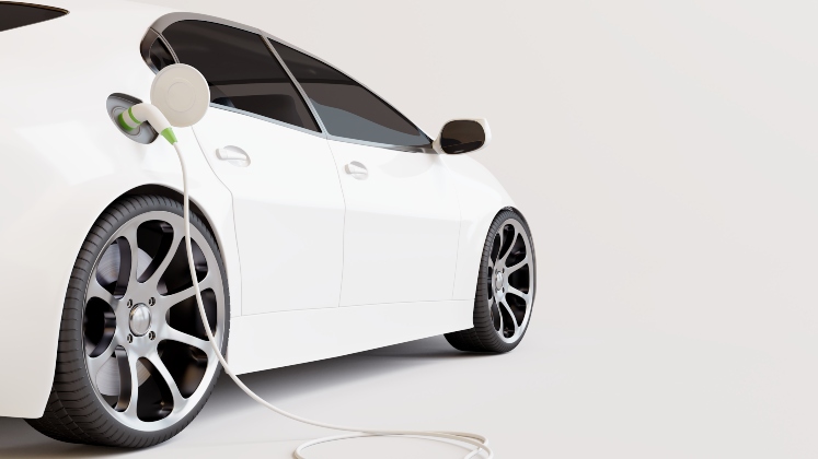 A white electric car plugged into a charging point.