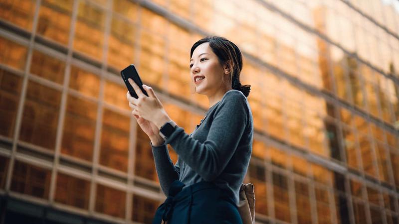 Woman goes to work and holds mobile phone near a building Entrepreneurial Finance