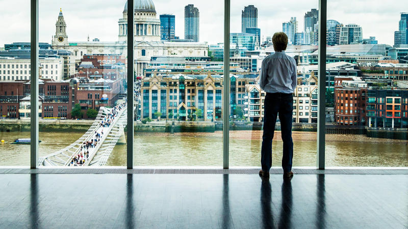 Businessman looking out of window at London skyline MBA Essentials