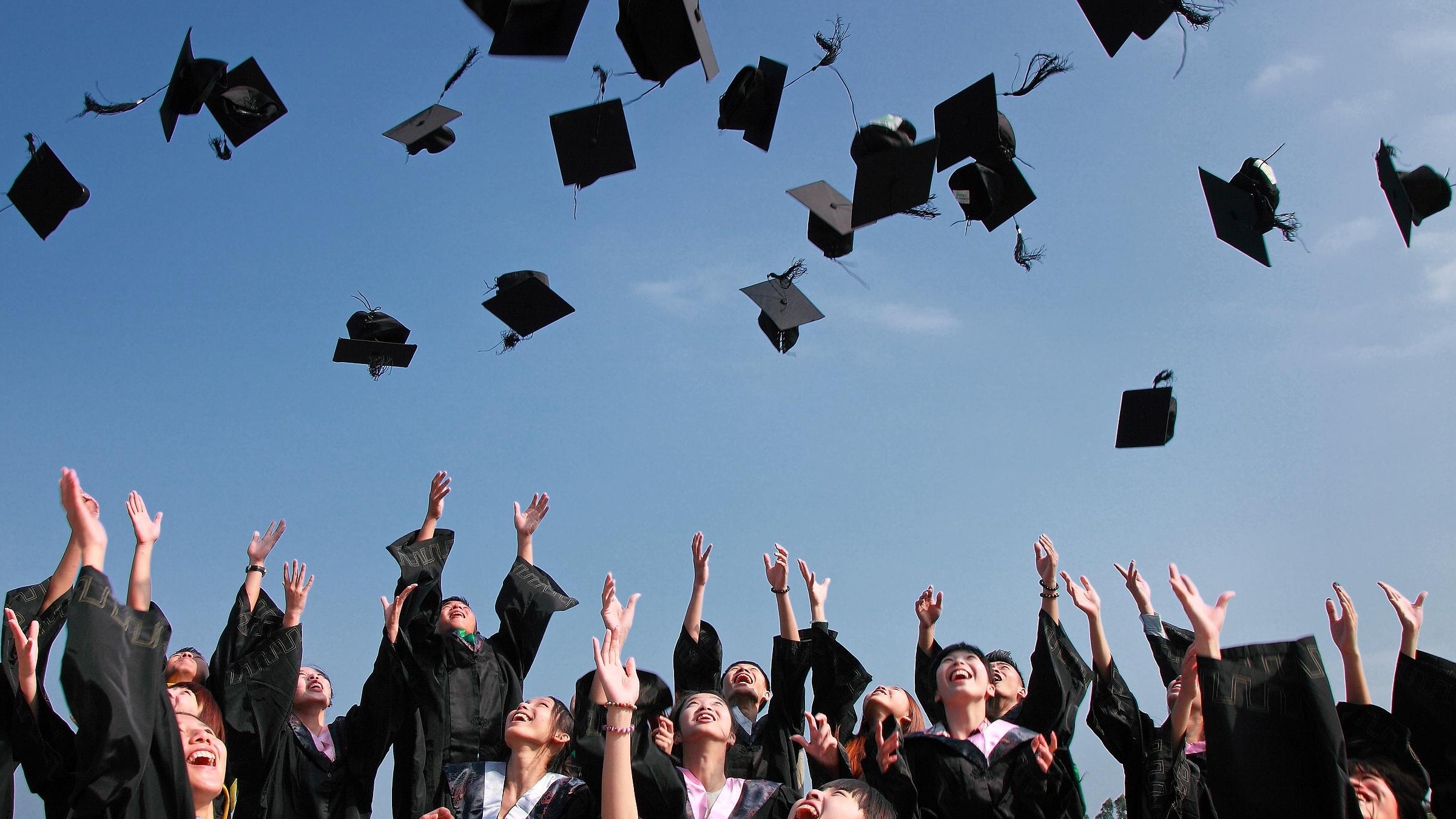 Graduates throwing their mortarboards in the air