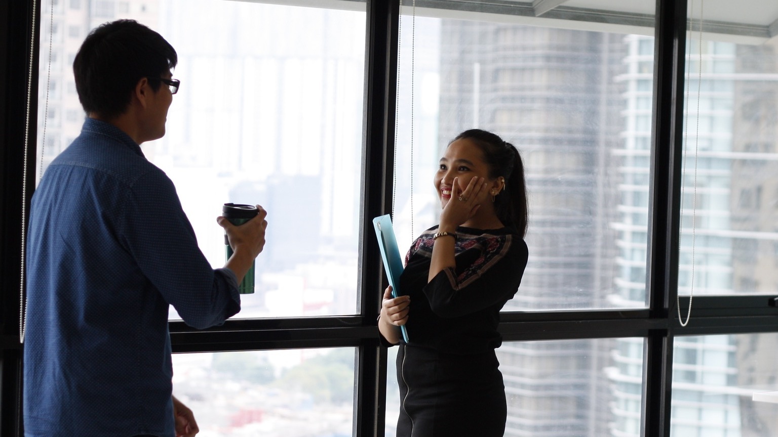 Two professionals in conversation by a window