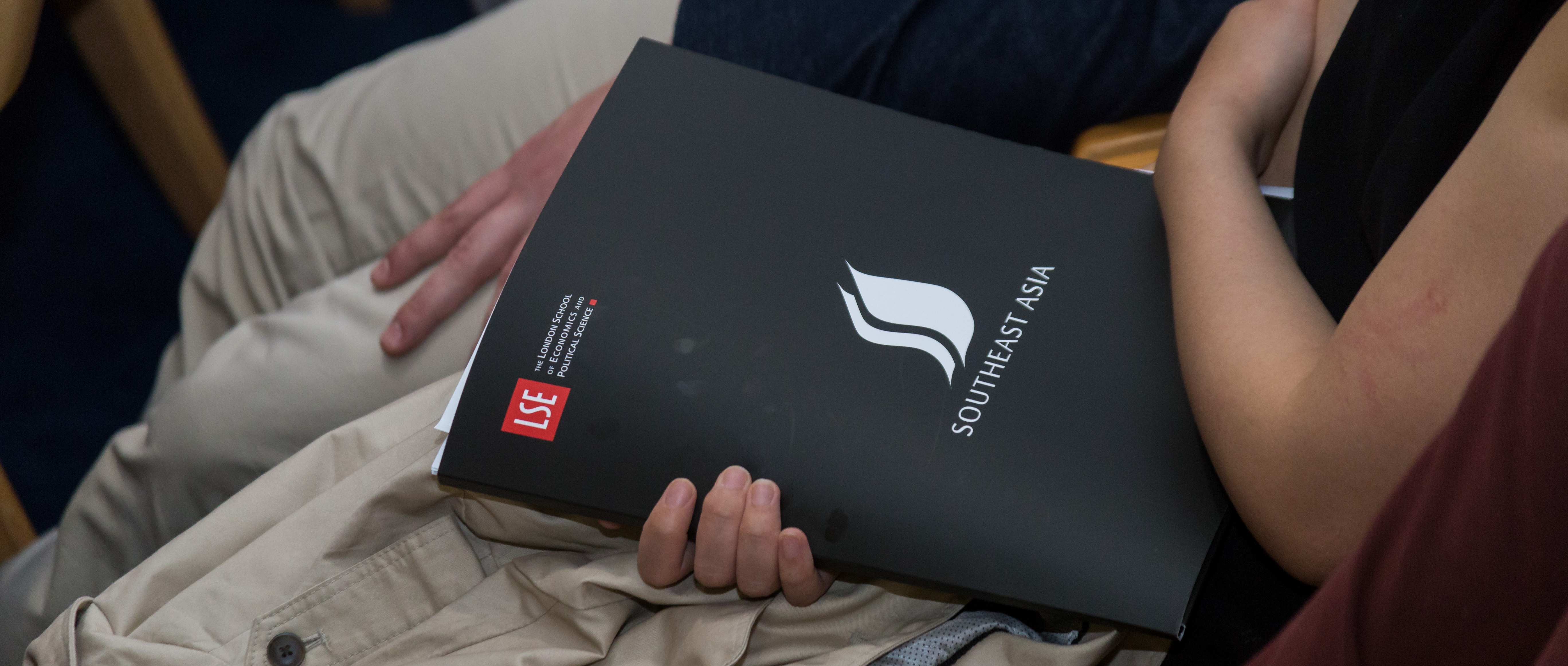 An audience member holding a branded LSE SEAC conference pack