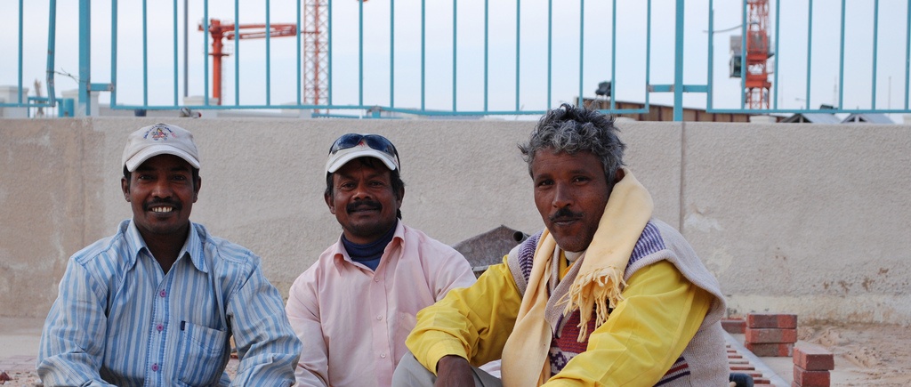 Three Middle Eastern migrants by a contruction site