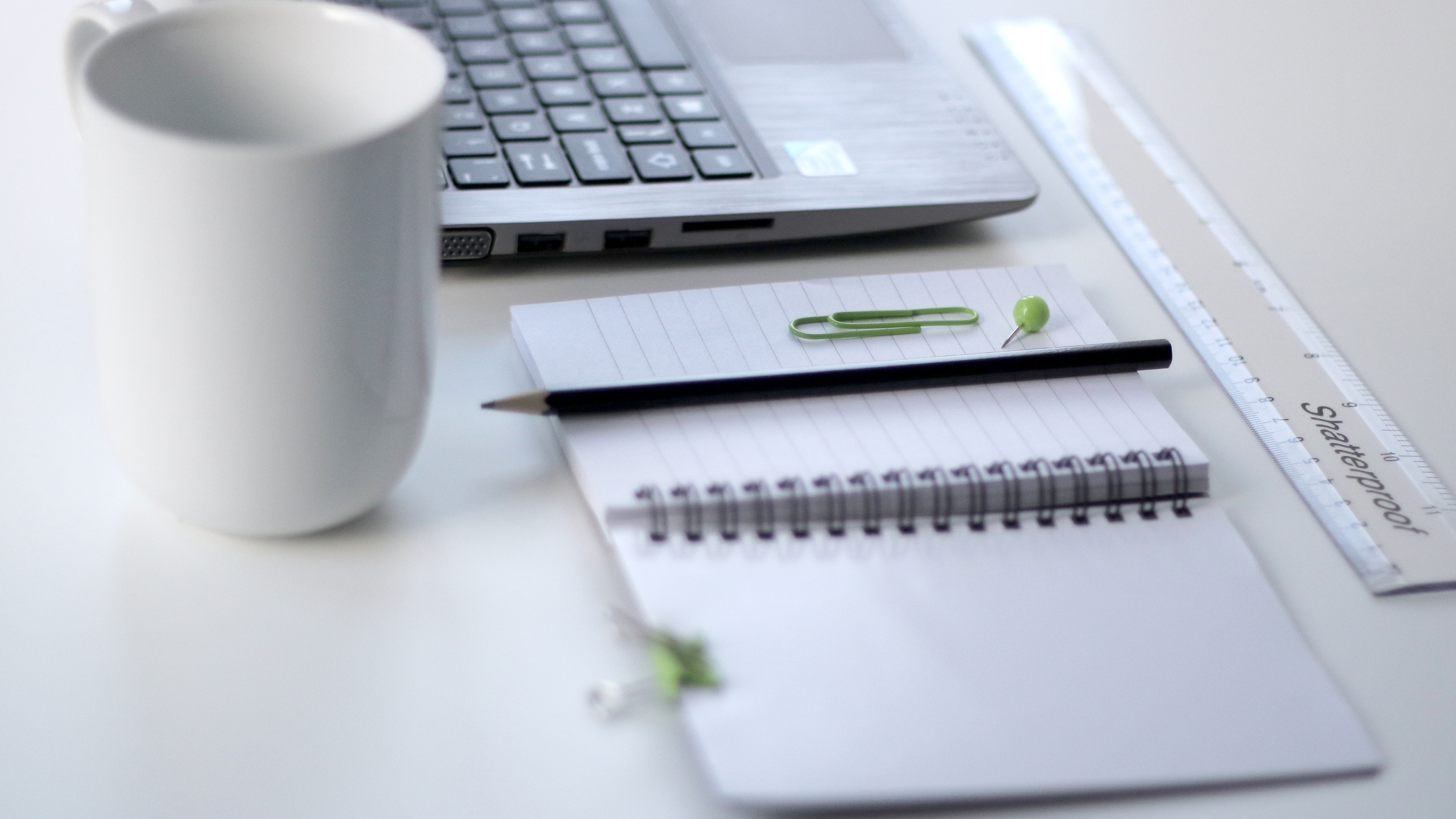 A mug, a laptop and some stationary on a desk