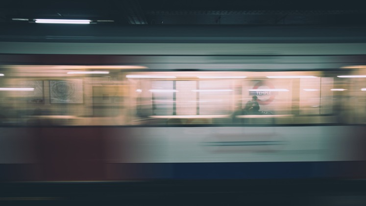 Blurry image of London underground train moving through station.