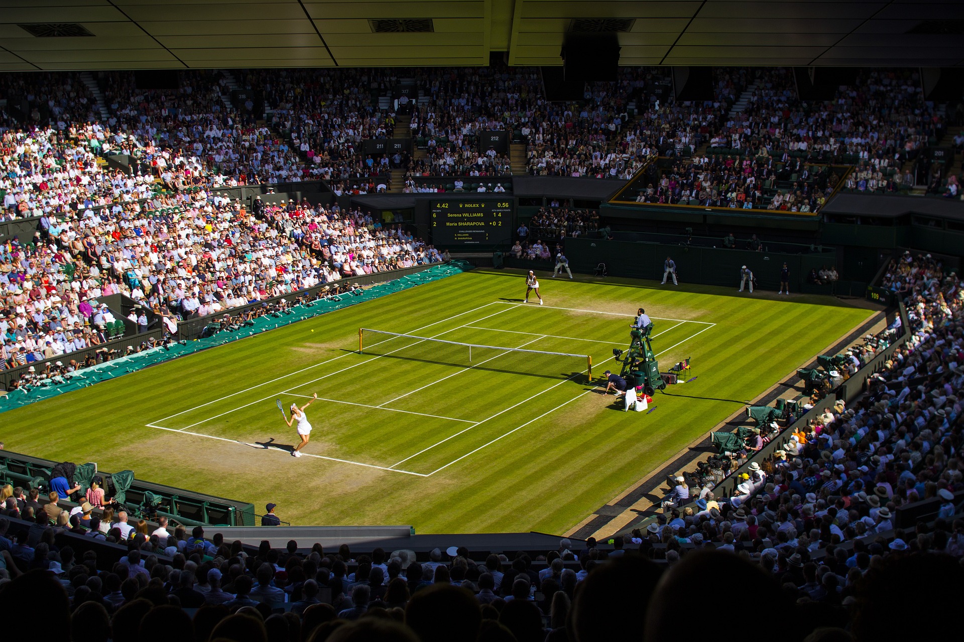 Wimbledon pitch with two women playing tennis whilst spectators look on