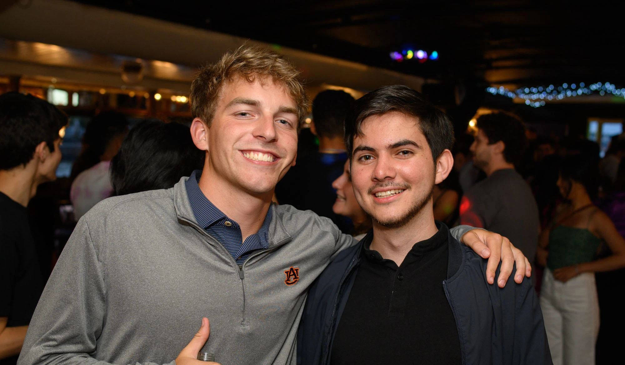 Two young men at a busy bar
