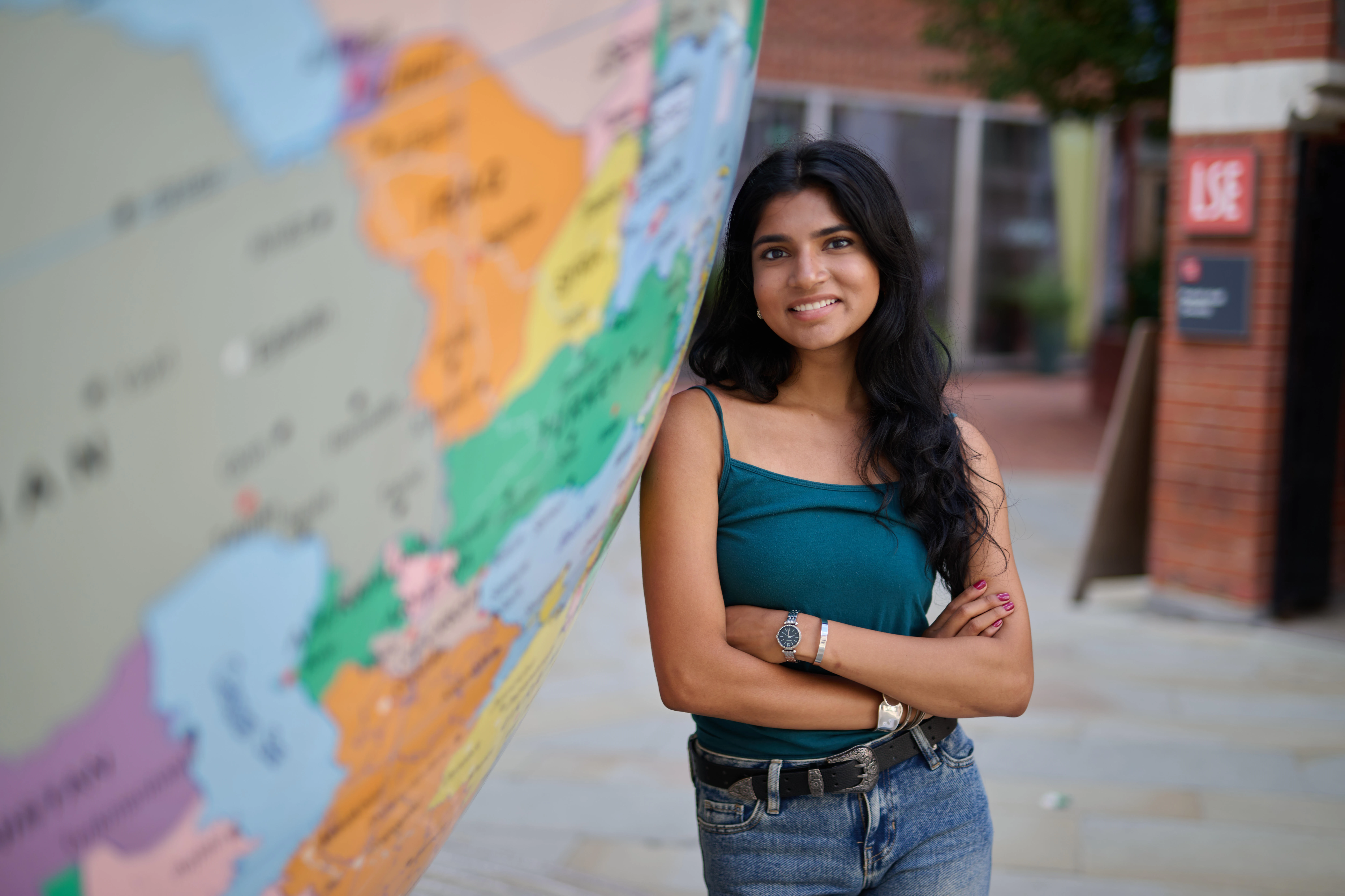 Student leaning against globe on LSE campus