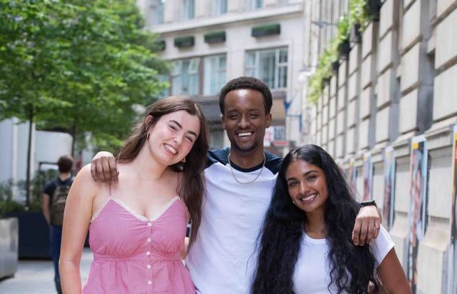 Three students smiling at camera on Houghton Street