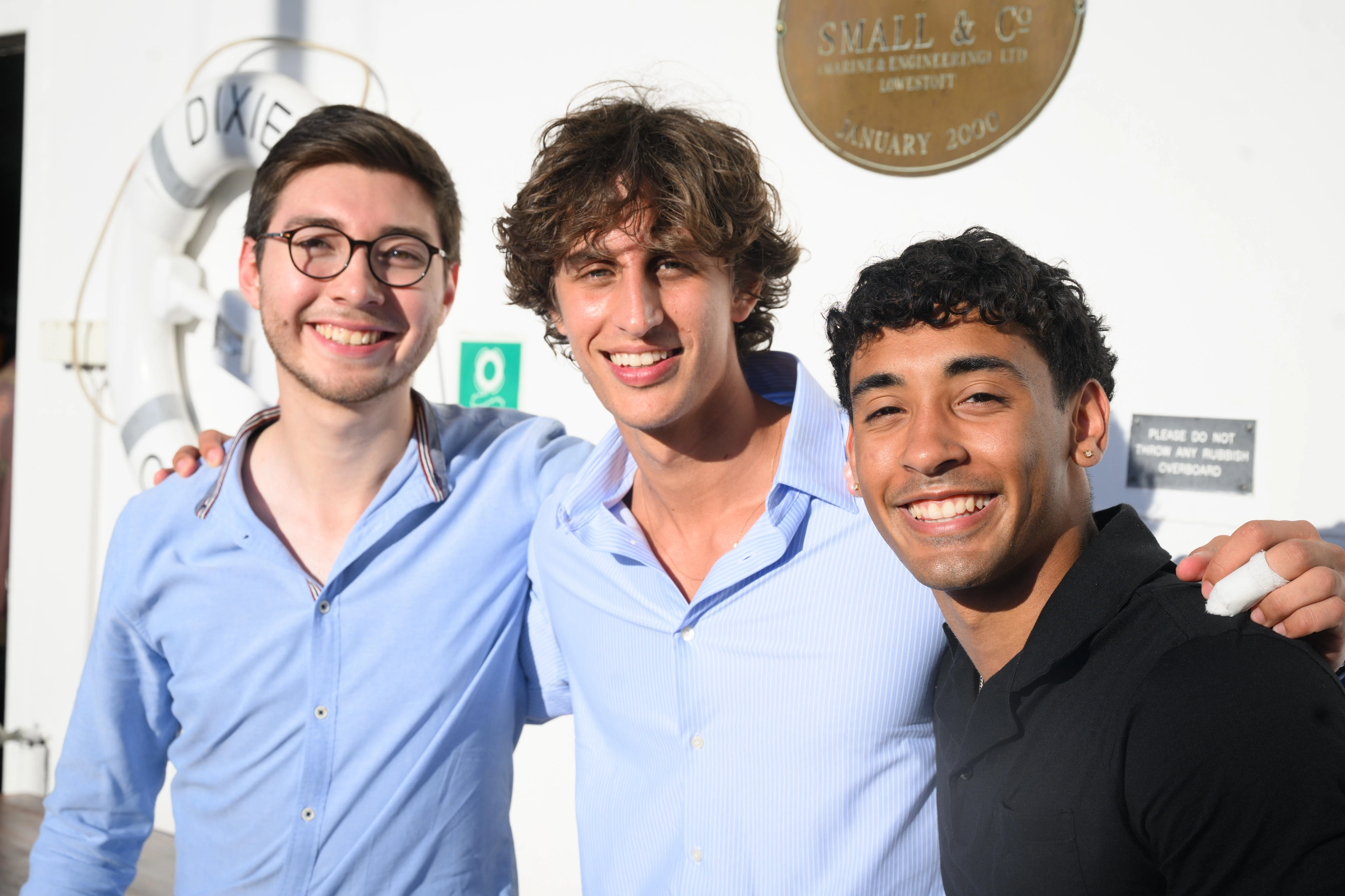 Three male students arms around each other