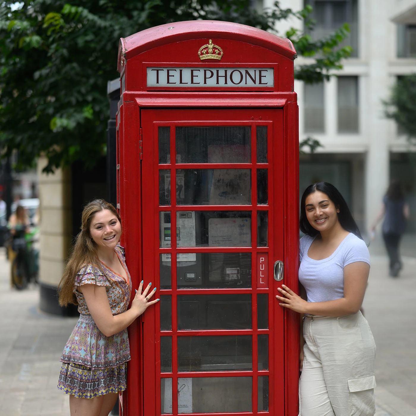 Two Summer School students standing next to a red telephone booth.